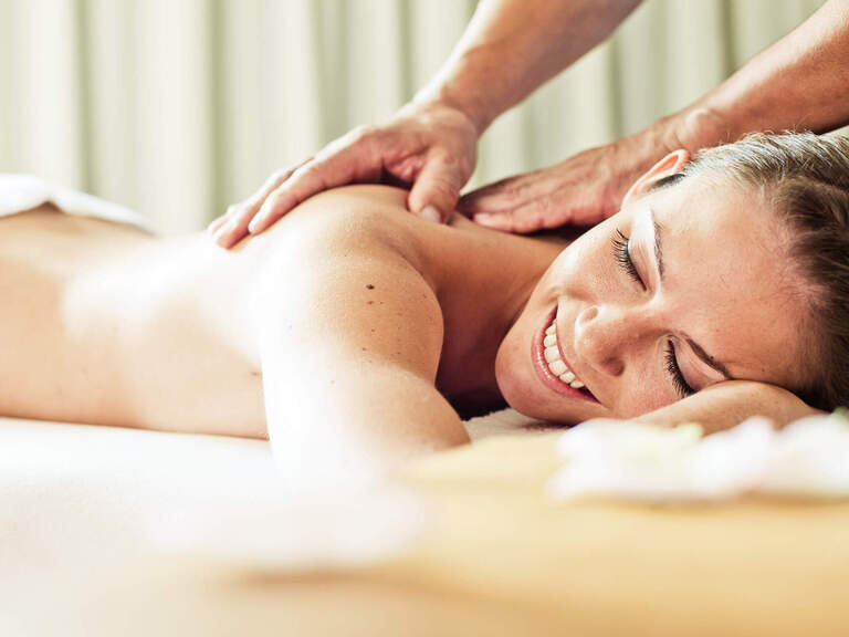 Eine glückliche Frau entspannt bei einer Massage in einem Wellnessbereich von einem Hotel in Bad Füssing.
